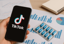 TikTok Is Just the Beginning: Why Context-First Pharma Media Strategy Matters Hand holding a smartphone with the TikTok app open, next to a blister pack of blue pills and data charts on a wooden desk.
