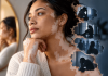 Vitiligo Is Visible. AbbVie Is Marketing What Patients Can’t See. Woman with vitiligo looking thoughtfully into the distance, with shadowy scenes representing anxiety, depression, and isolation, highlighting the hidden emotional burden of the condition.